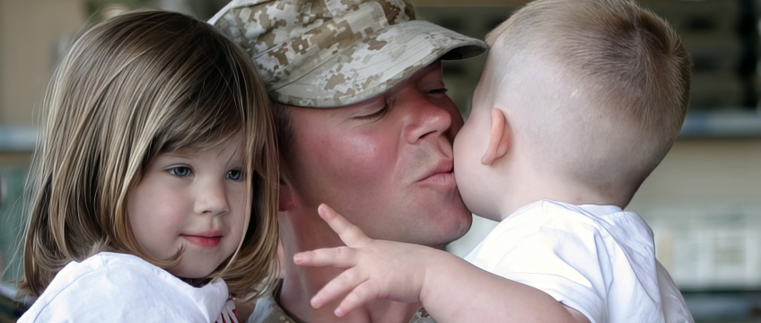 a soldier holding two children