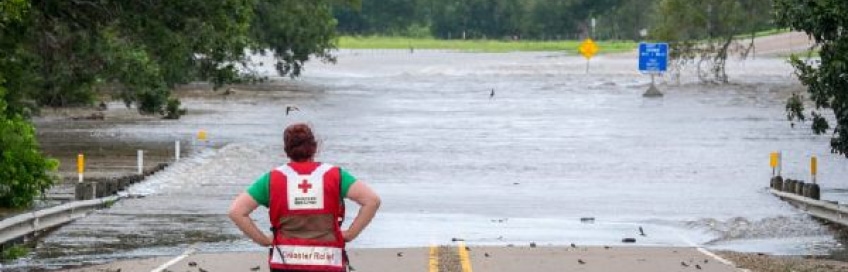 red cross volunteer standing in front of flooding
