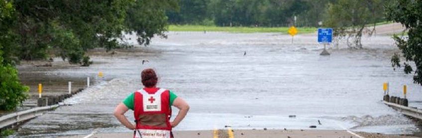 red cross volunteer standing in front of flooding